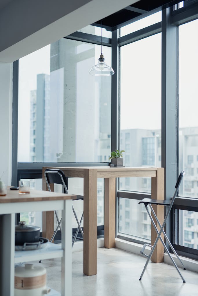 Bright modern apartment interior featuring minimalist wooden furniture and a glass window with a cityscape view.